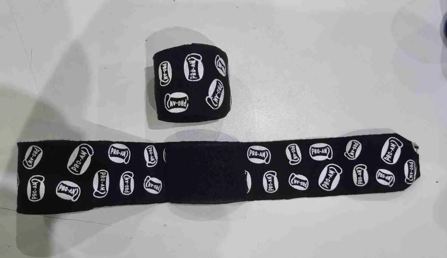 Pro-Am Stretch Boxing Hand Wraps by Proamboxinguk, showing black and white elastic hand wraps for boxing training and protection.