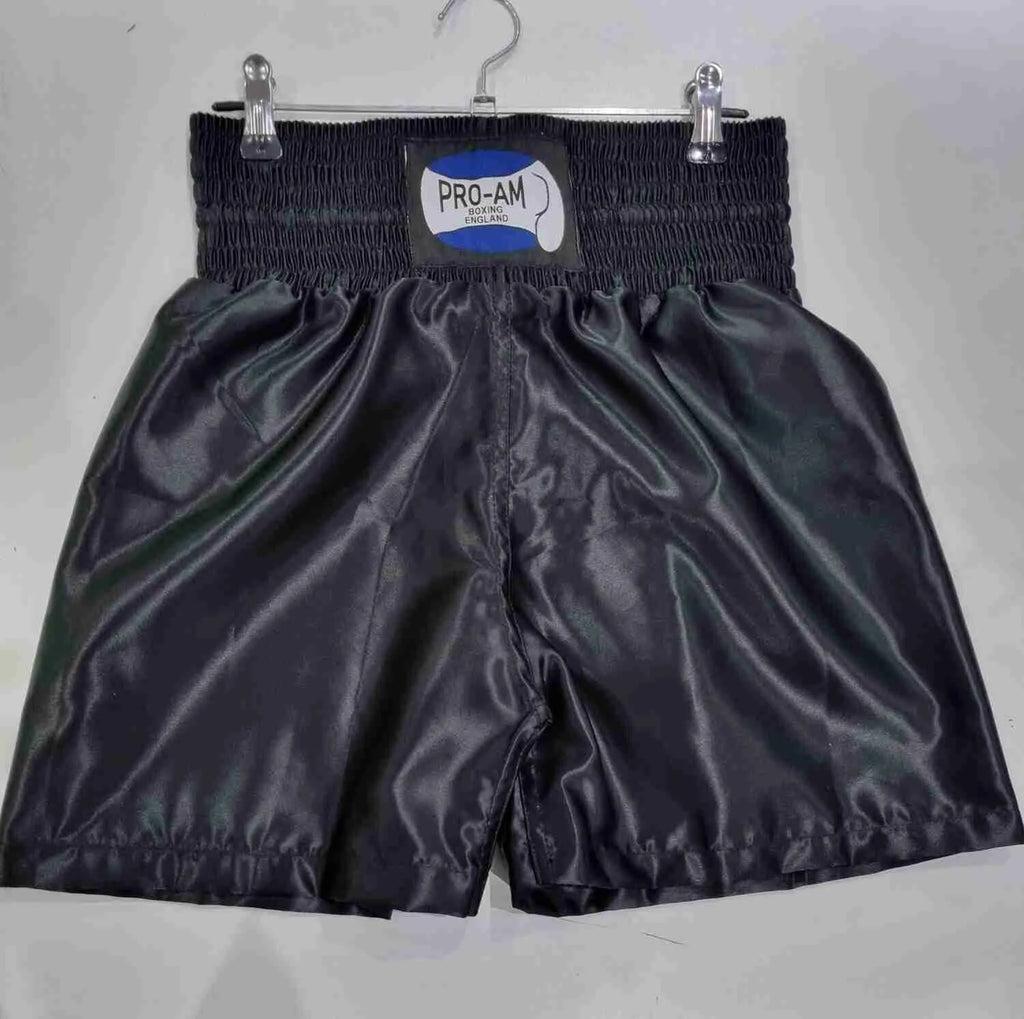 Pro-Am Satin Boxing Shorts in black with white trim, featuring the Proamboxinguk logo and comfortable waistband.