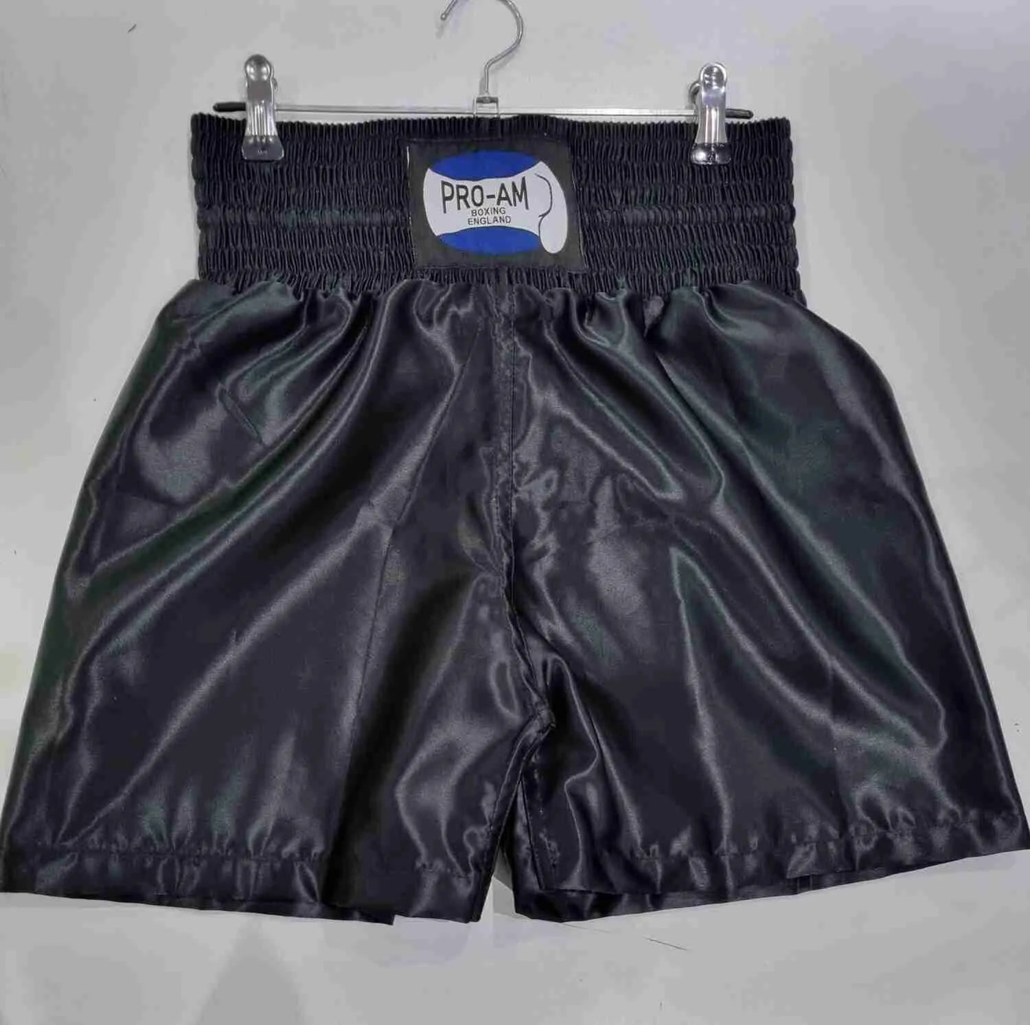 Pro-Am Satin Boxing Shorts in black with white trim, featuring the Proamboxinguk logo and comfortable waistband.