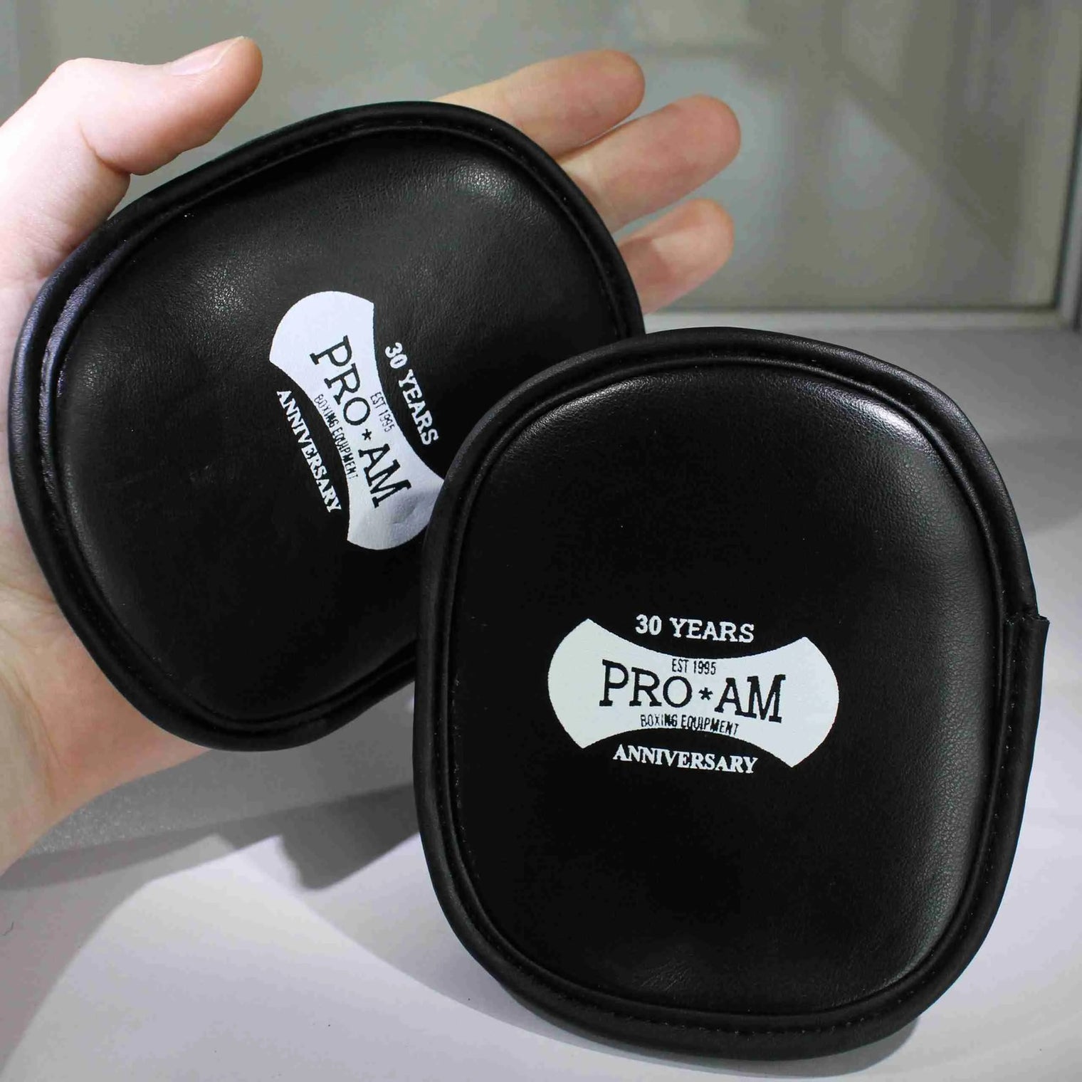 Pro-Am Palm Pads for boxing training, showing black and red padded gloves with adjustable straps, used for boxing practice and drills.