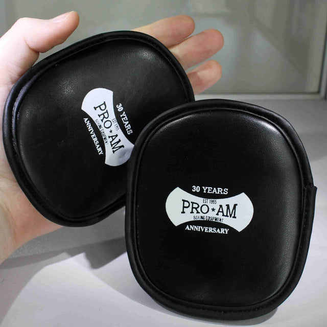 Pro-Am Palm Pads for boxing training, showing black and red padded gloves with adjustable straps, used for boxing practice and drills.